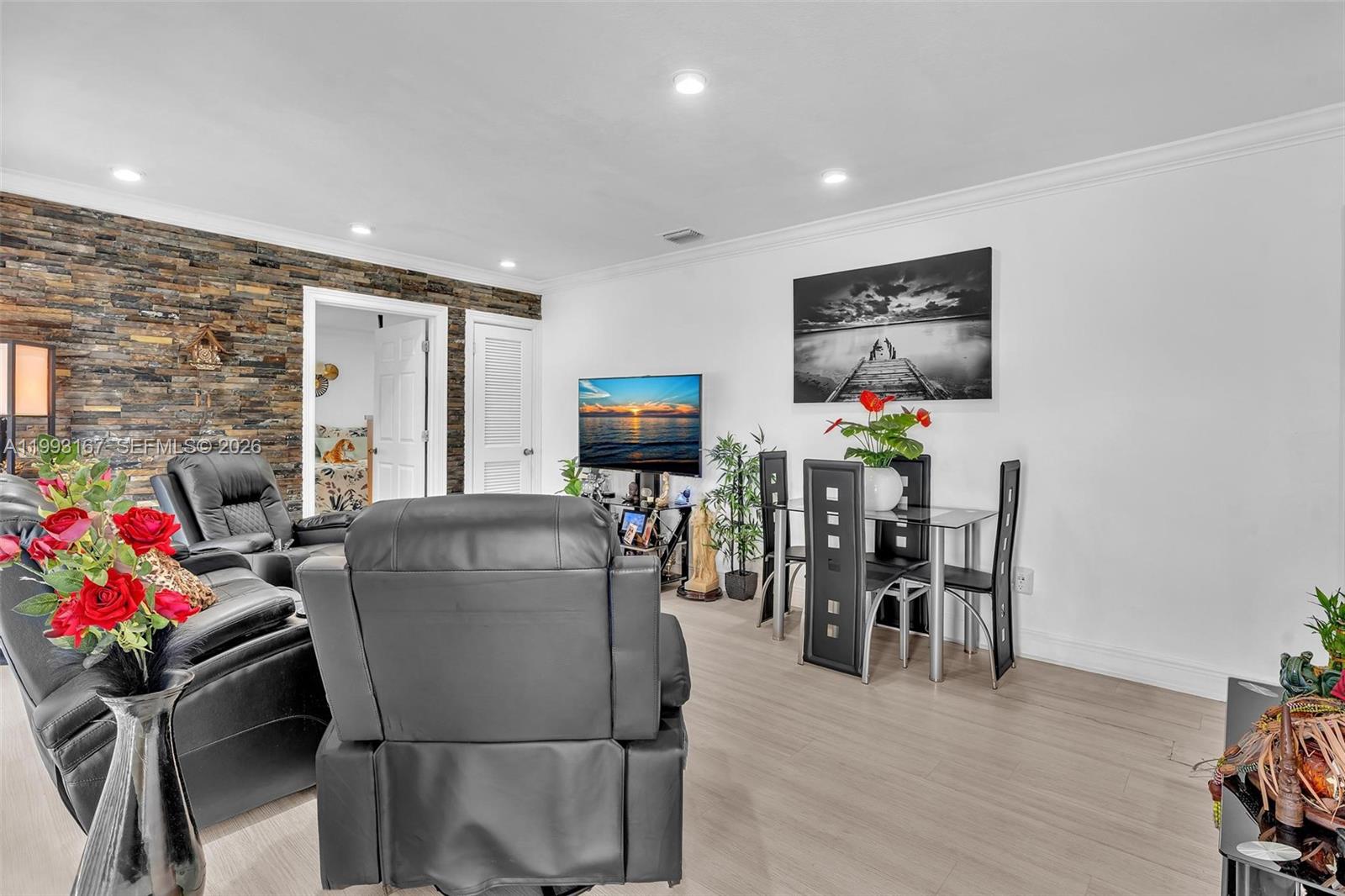 A living and dining area features a stone accent wall, leather furniture, and light flooring — 340 W 55th St, Hialeah FL 33012, HIALEAH, FL