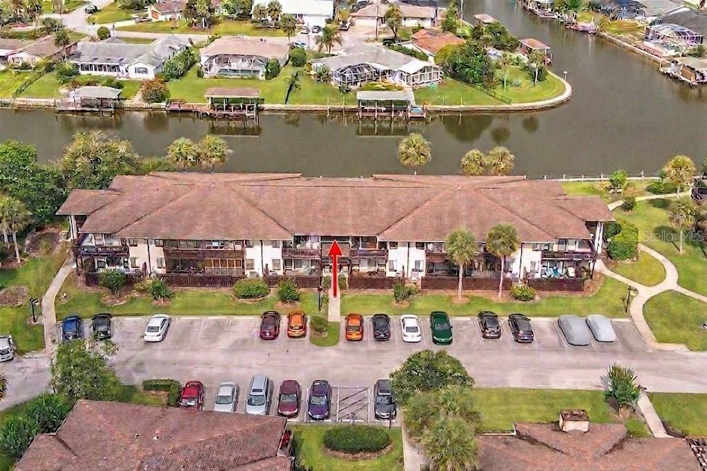 An aerial view shows a multi-story apartment building with a parking lot and canal — 42 CLUB HOUSE DRIVE UNIT 207, PALM COAST, FL