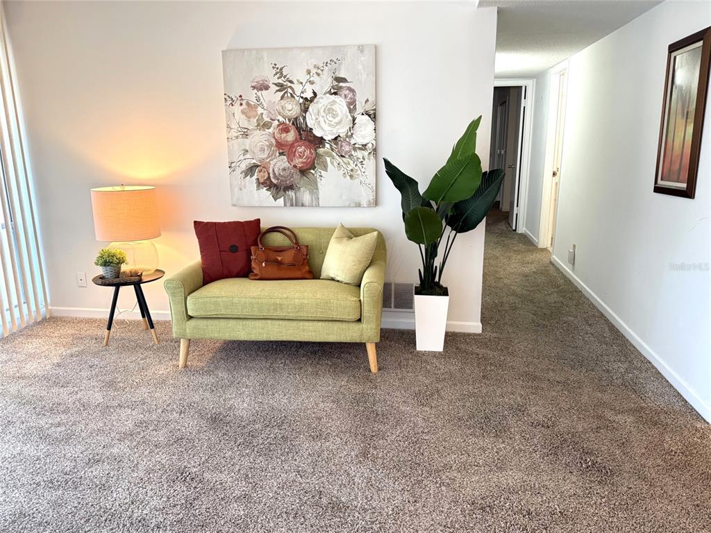 A living area features a green loveseat, a side table with a lamp, and a plant — 42 CLUB HOUSE DRIVE UNIT 207, PALM COAST, FL