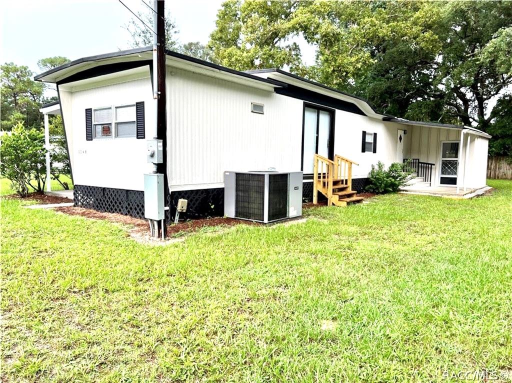 A white mobile home with black trim, a central air unit, and wooden steps — 3249 S CALAIS TERRACE, HOMOSASSA, FL