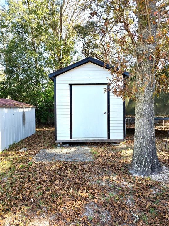 A white shed with a black-trimmed door stands in a yard covered with fallen leaves — 3249 S CALAIS TERRACE, HOMOSASSA, FL