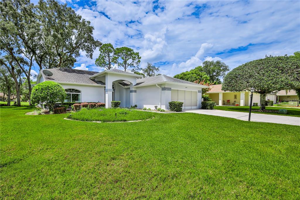 A single-story white house with a two-car garage and a large front lawn — 8018 SUGARBUSH DRIVE, SPRING HILL, FL