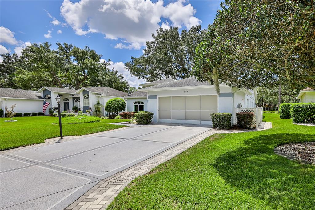 A single-story house with a large garage, a paved driveway, and a manicured green lawn — 8018 SUGARBUSH DRIVE, SPRING HILL, FL