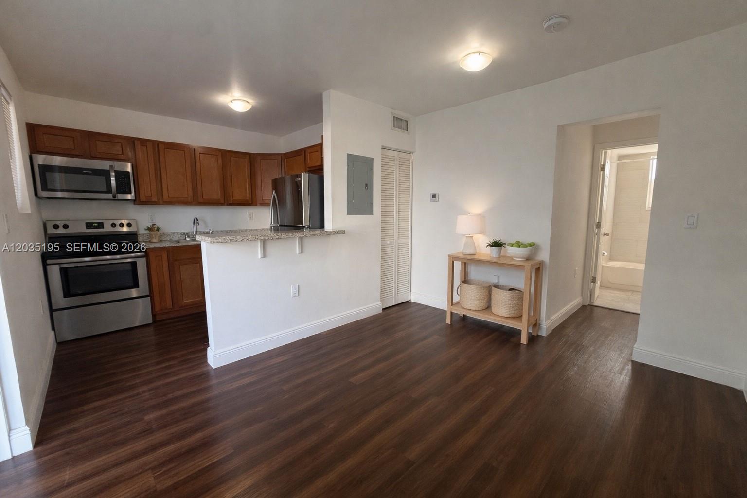 A kitchen with wood cabinets and stainless steel appliances opens to a living area — 540 NW 7th St # 49, Miami FL 33136, MIAMI, FL