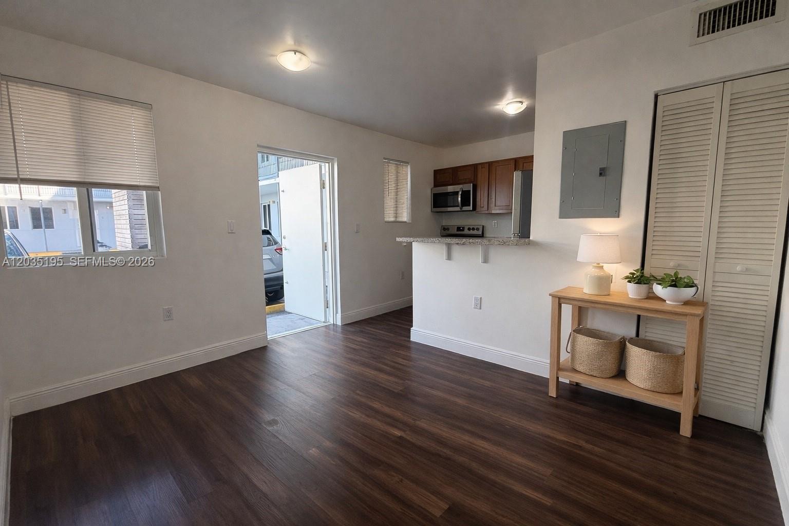 This room features dark wood-look flooring, a kitchen with a breakfast bar, and an exterior door — 540 NW 7th St # 49, Miami FL 33136, MIAMI, FL