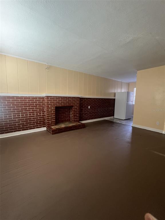 A room with a brick fireplace, wood-paneled walls, and a visible refrigerator in the background — 5353 N ORANGE BLOSSOM TRAIL, MOUNT DORA, FL