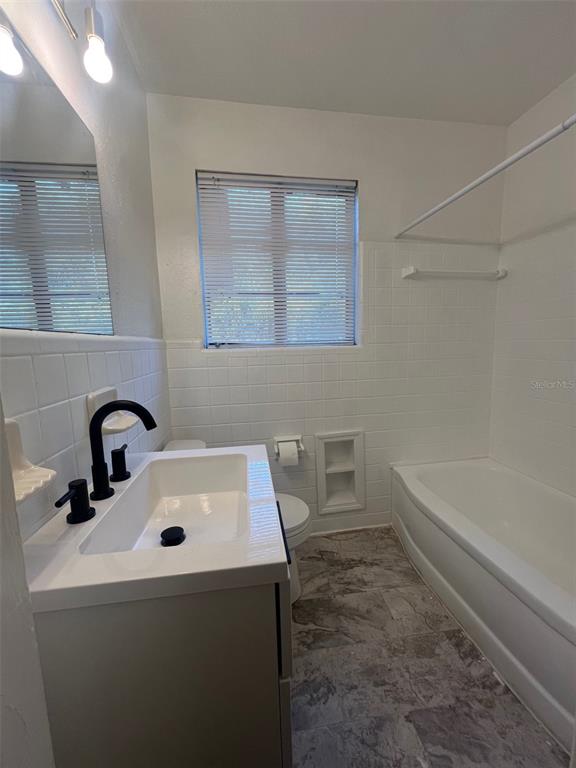 A bathroom features a white vanity with a black faucet, a toilet, and a tub — 5353 N ORANGE BLOSSOM TRAIL, MOUNT DORA, FL