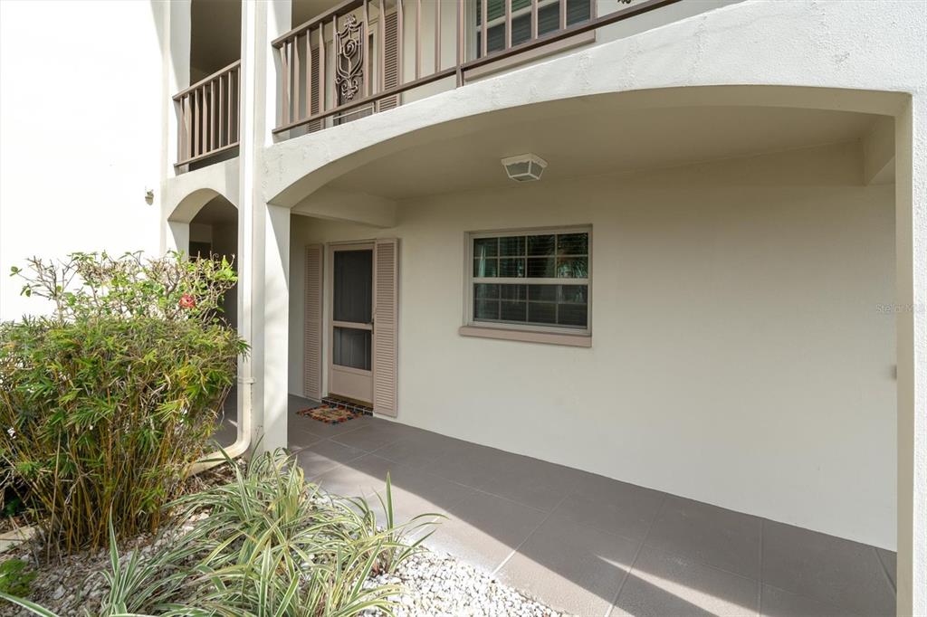 A covered patio entrance features a screen door, a window, and tiled flooring — 19029 US HIGHWAY 19 N UNIT 7-8, CLEARWATER, FL
