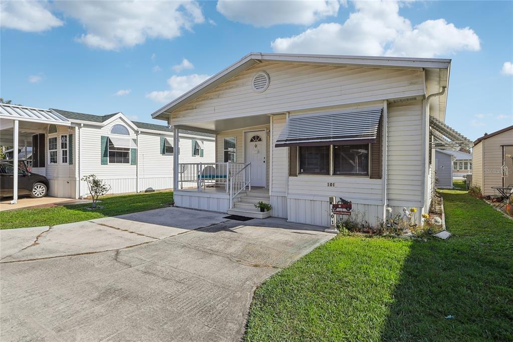 A single-story manufactured home with white siding, a front porch, and a concrete driveway — 101 CITRUS RIDGE DRIVE, DAVENPORT, FL