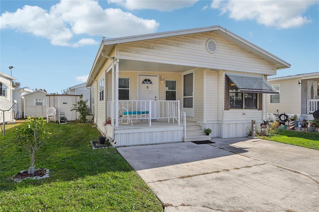 A single-story manufactured home with a front porch, concrete driveway, and light-colored siding — 101 CITRUS RIDGE DRIVE, DAVENPORT, FL