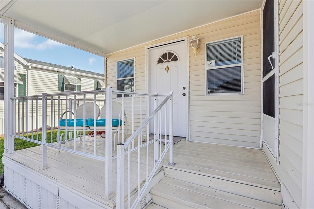 A white front door with a small window sits on a porch with white railings — 101 CITRUS RIDGE DRIVE, DAVENPORT, FL
