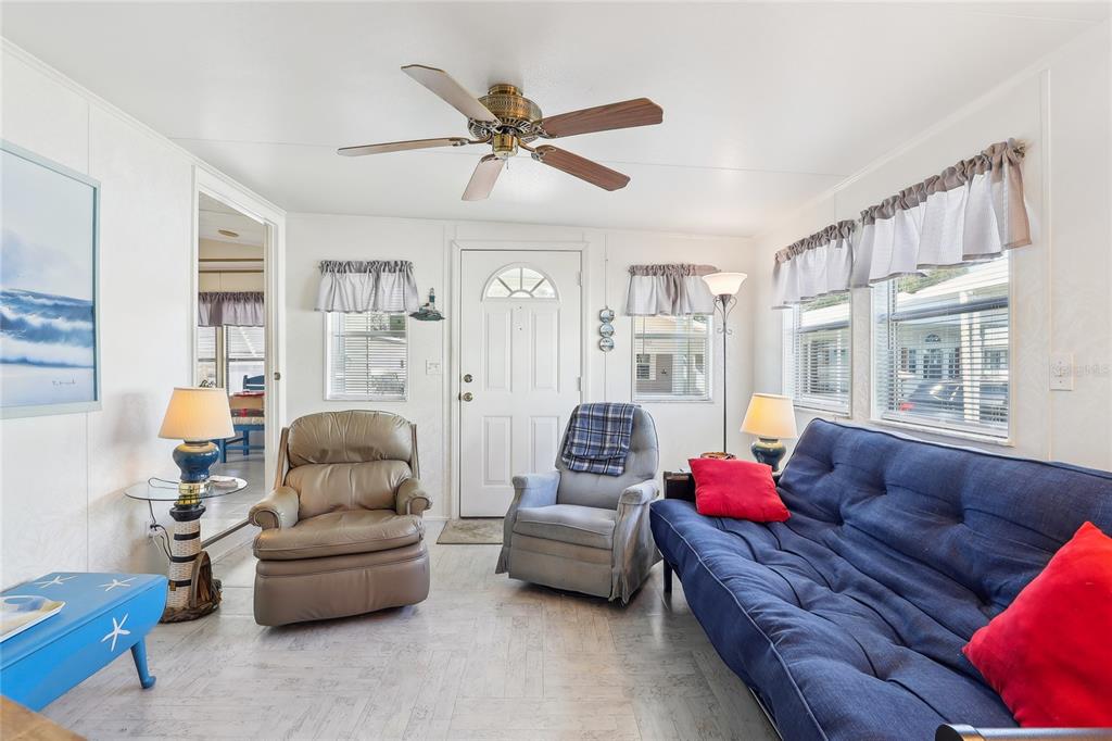 A living room features a blue sofa, two armchairs, a ceiling fan, and white walls — 101 CITRUS RIDGE DRIVE, DAVENPORT, FL