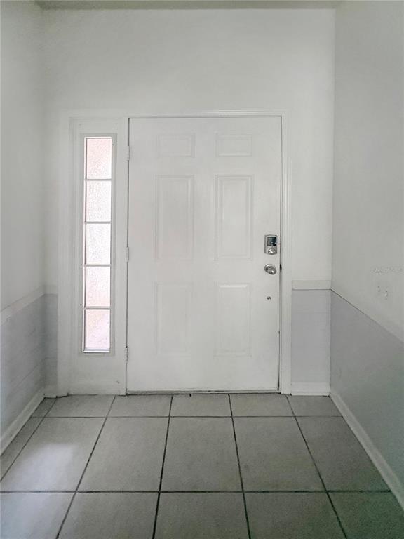 An entryway features a white front door with a sidelight, tiled flooring, and wainscoting — 4924 CHATHAM GATE DRIVE, RIVERVIEW, FL