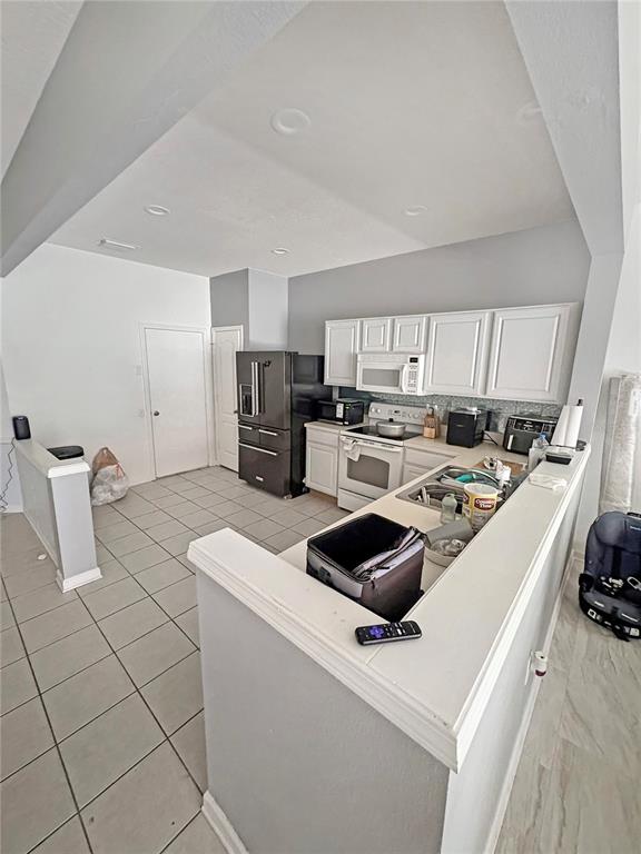 A kitchen features white cabinetry, stainless steel appliances, and a tiled floor — 4924 CHATHAM GATE DRIVE, RIVERVIEW, FL