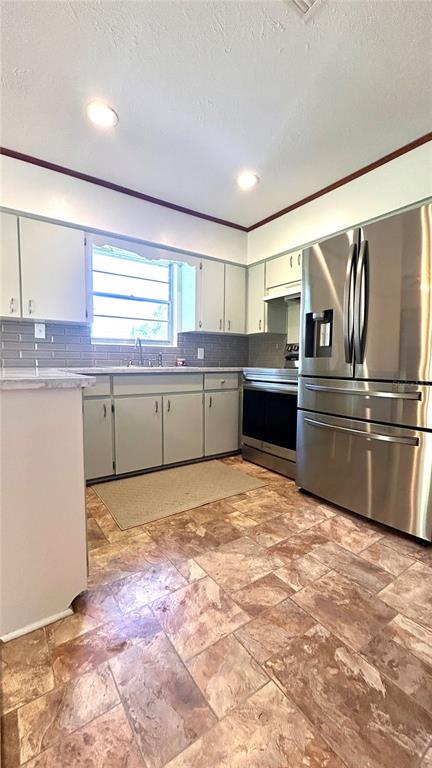 A kitchen features light gray cabinets, stainless steel appliances, and brown tile flooring — 234 SW HAVANNA WAY, LAKE CITY, FL