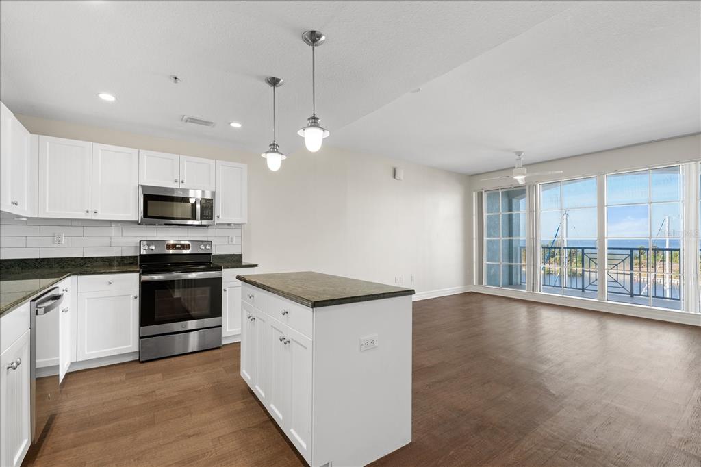 A kitchen with white cabinets and a dark island overlooks a living area with balcony views — 536 BAHIA BEACH BOULEVARD UNIT 422B, RUSKIN, FL