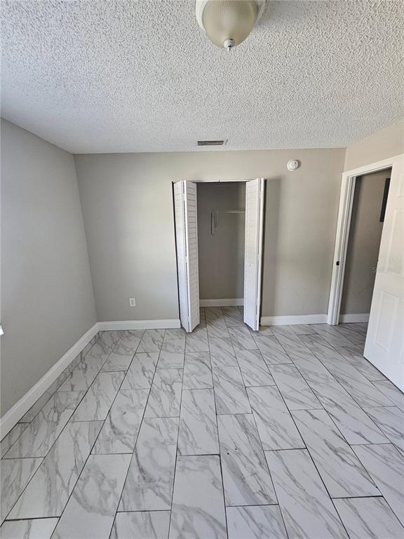 A bedroom with gray walls, white trim, and white marble-look tile flooring — 1013 BEECHER STREET Unit 1, LEESBURG, FL