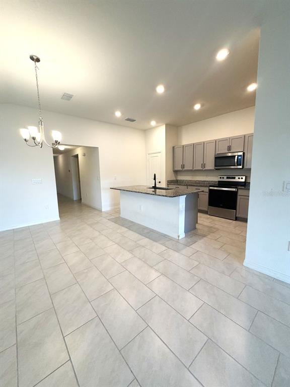 A kitchen with gray cabinets, granite countertops, and an island opens to a dining area — 925 OVERPOOL AVENUE, DAVENPORT, FL