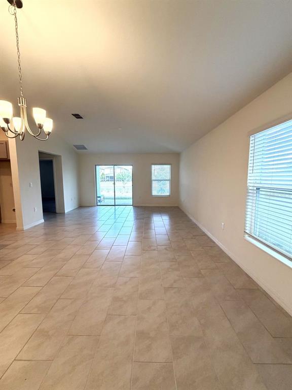 An open-concept living area features light-colored tile flooring, a chandelier, and sliding glass doors — 925 OVERPOOL AVENUE, DAVENPORT, FL