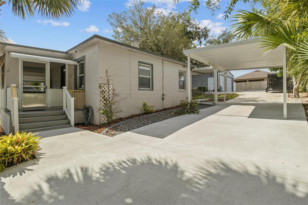 A single-story house with a concrete block exterior, a front porch, and a metal carport — 205 W MAPLE STREET, DAVENPORT, FL