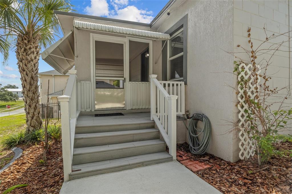 A wooden staircase leads to a screened-in porch entrance on the side of a house — 205 W MAPLE STREET, DAVENPORT, FL