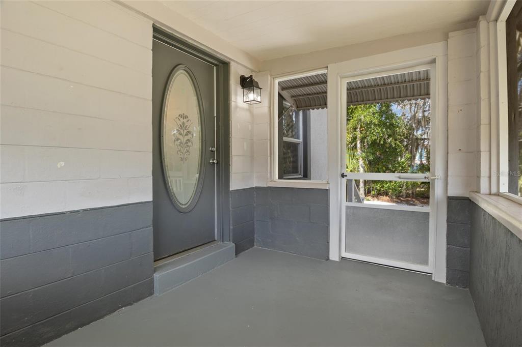 A covered porch features a gray front door with an oval window and a screen door — 205 W MAPLE STREET, DAVENPORT, FL
