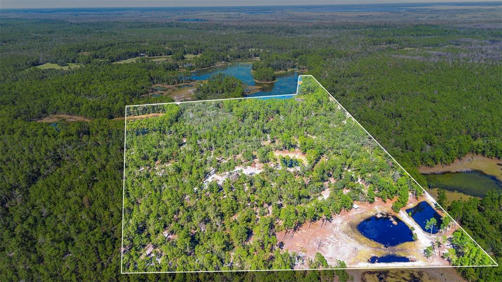 An aerial view shows a large, wooded plot of land with several small ponds — DEEP WOODS ROAD, PAISLEY, FL