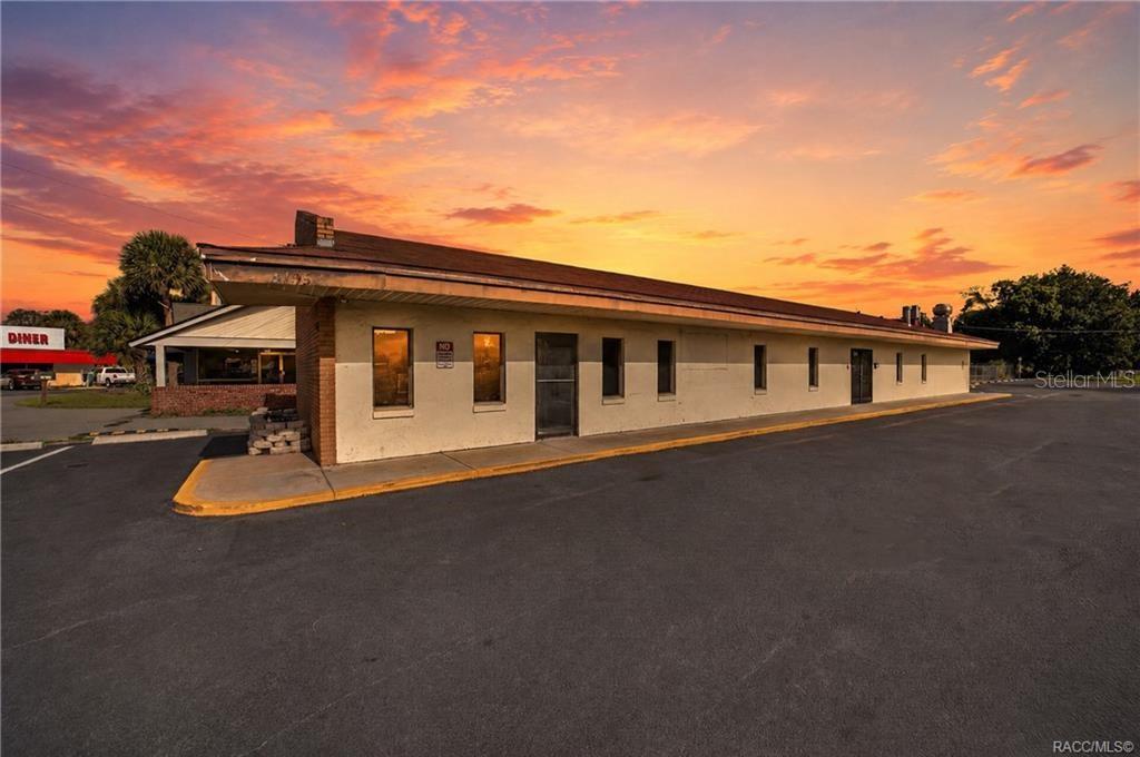 A long, single-story commercial building with a flat roof and asphalt parking lot at sunset — 5195 E SILVER SPRINGS BOULEVARD, SILVER SPRINGS, FL