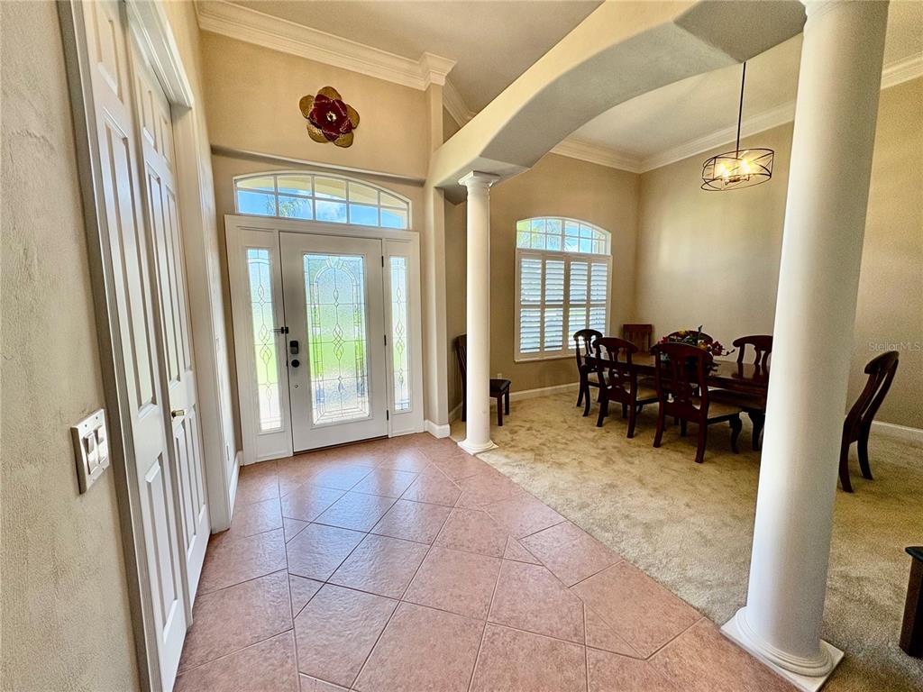 An entryway with tile flooring leads to a dining room featuring carpet and decorative columns — 800 STERLING CHASE DRIVE, PORT ORANGE, FL