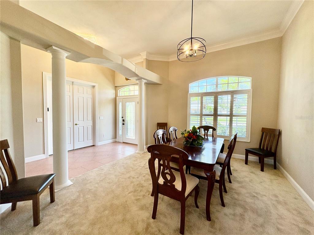 A dining room features a wooden table, chairs, carpeted flooring, and a decorative arched column — 800 STERLING CHASE DRIVE, PORT ORANGE, FL