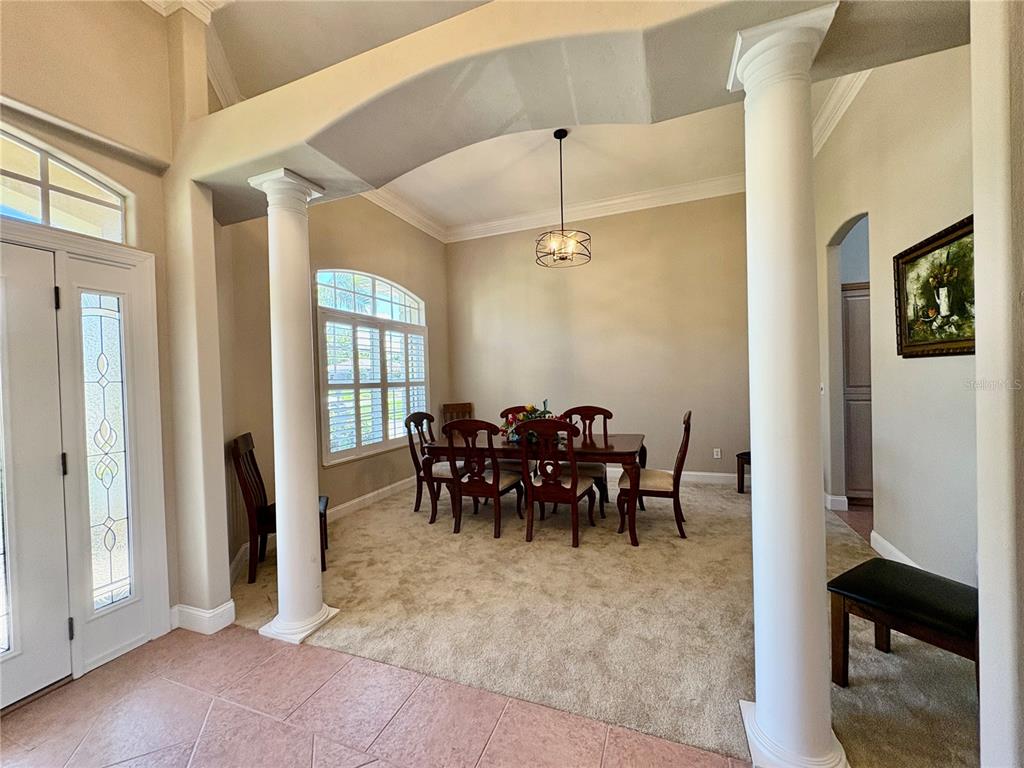 A dining room features carpeted floors, white columns, a vaulted ceiling, and a chandelier — 800 STERLING CHASE DRIVE, PORT ORANGE, FL