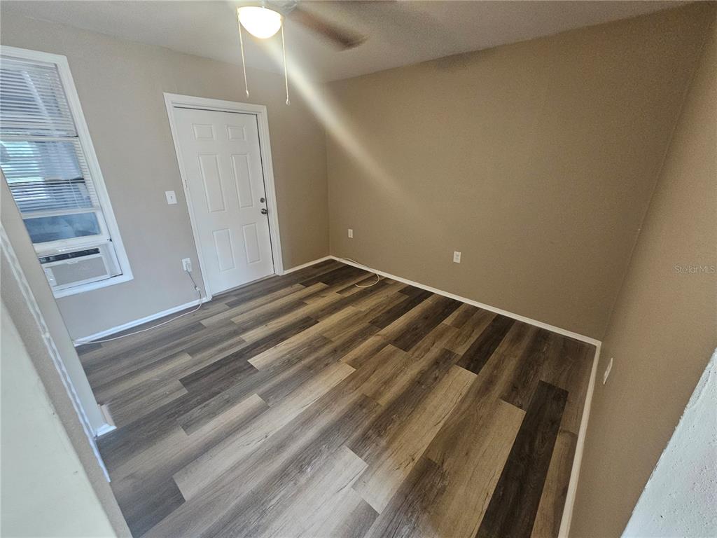 An empty room features light brown walls, a white door, and wood-look plank flooring — 318 E TARPON AVENUE UNIT A1, TARPON SPRINGS, FL