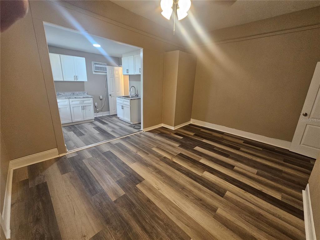 An interior view shows a living area with wood-look flooring leading into a small kitchen — 318 E TARPON AVENUE UNIT A1, TARPON SPRINGS, FL