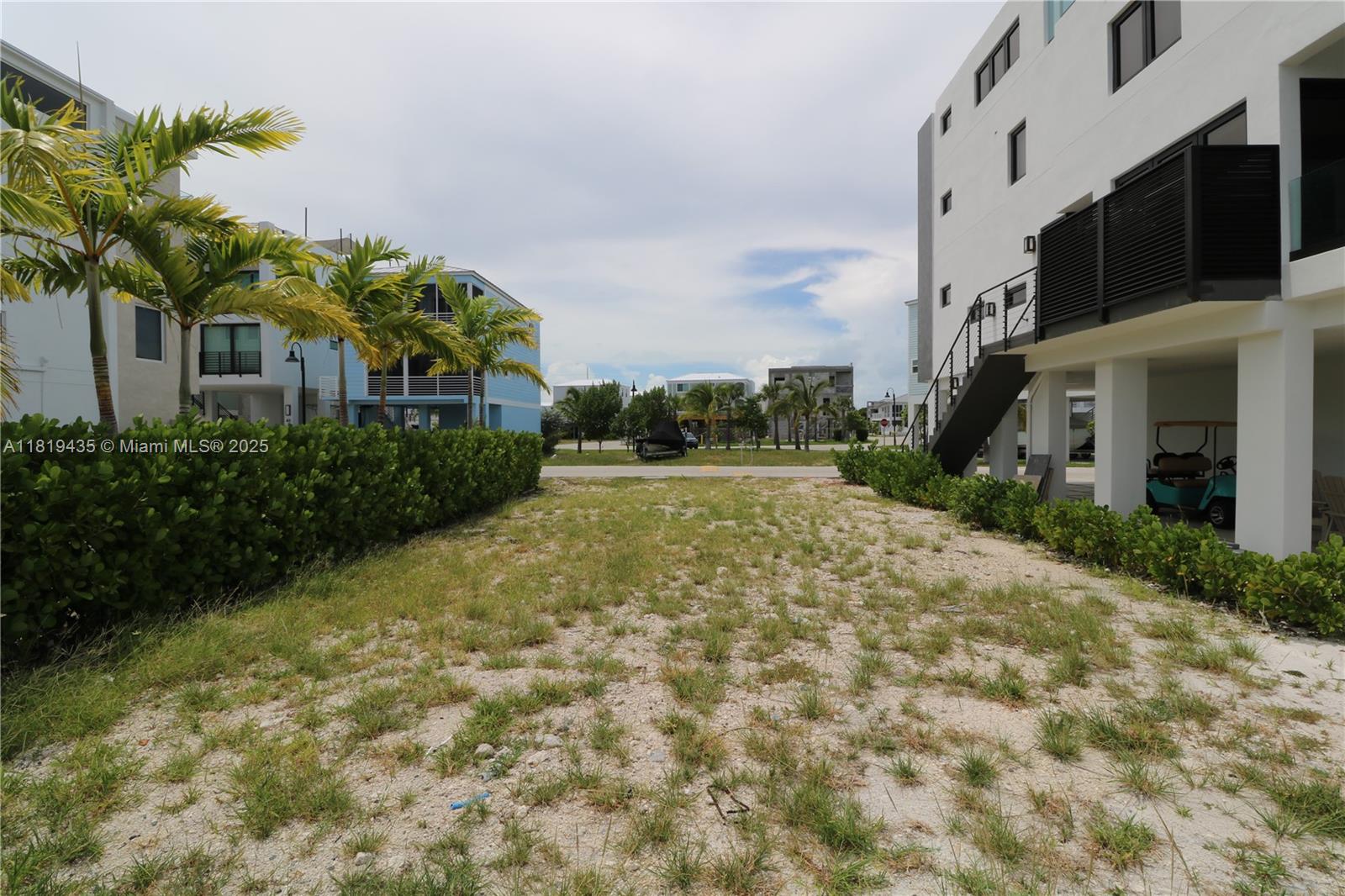 A vacant sandy lot sits between two modern multi-story buildings with palm trees and landscaping — 94825 Overseas Hwy #35, Key Largo FL 33037, KEY LARGO, FL