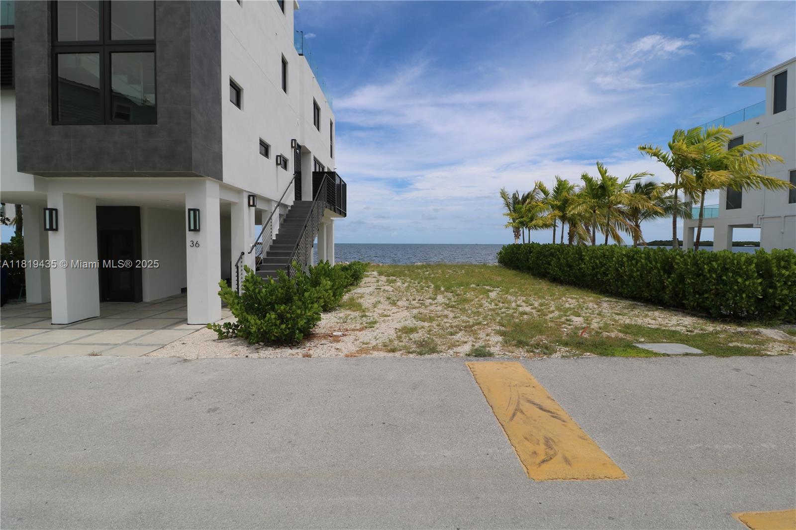 A modern multi-story building stands next to a sandy path leading toward the ocean — 94825 Overseas Hwy #35, Key Largo FL 33037, KEY LARGO, FL