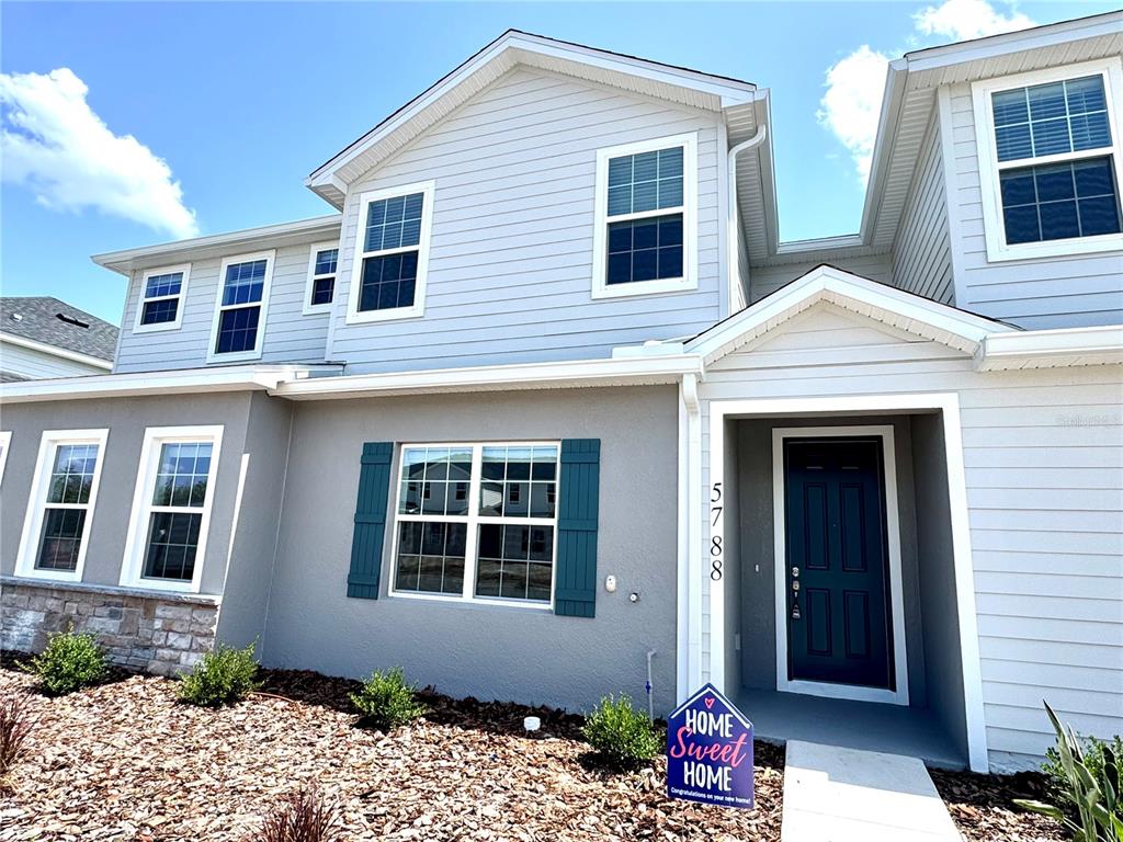 A two-story house with light gray siding, a dark blue front door, and a landscaped yard — 5788 FRESHWATER CANYON DRIVE, ST CLOUD, FL