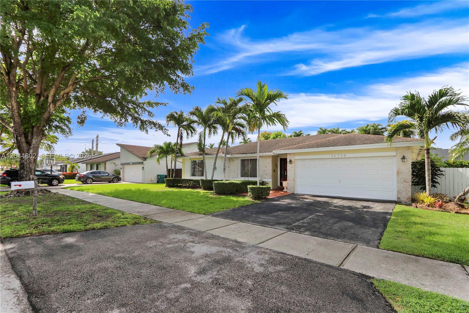 A single-story house with a white garage, stone facade, and palm trees in the front yard — 12730 SW 119th St, Miami FL 33186, MIAMI, FL