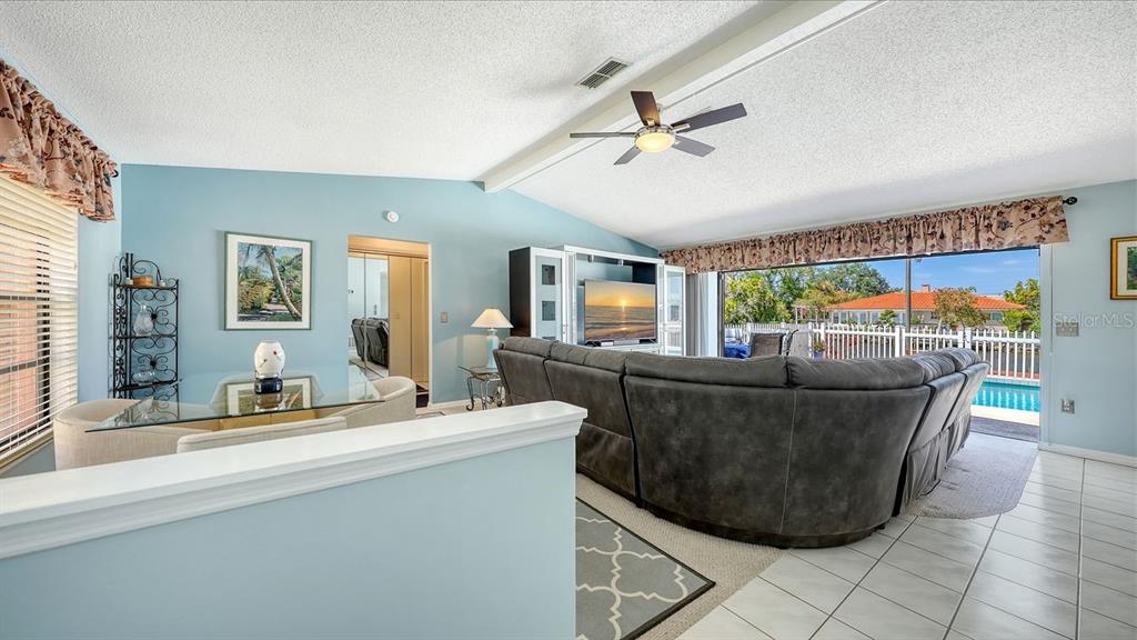 A living room with a gray sectional sofa, dining area, and sliding doors to a pool — 723 PORTIA STREET N, NOKOMIS, FL