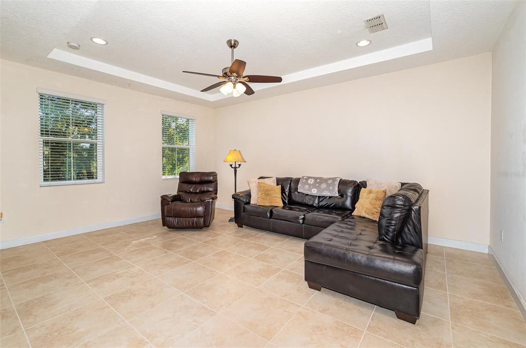 A living room features beige tile flooring, a dark leather sectional, and a recliner — 669 HANGNEST LANE, LAKE MARY, FL