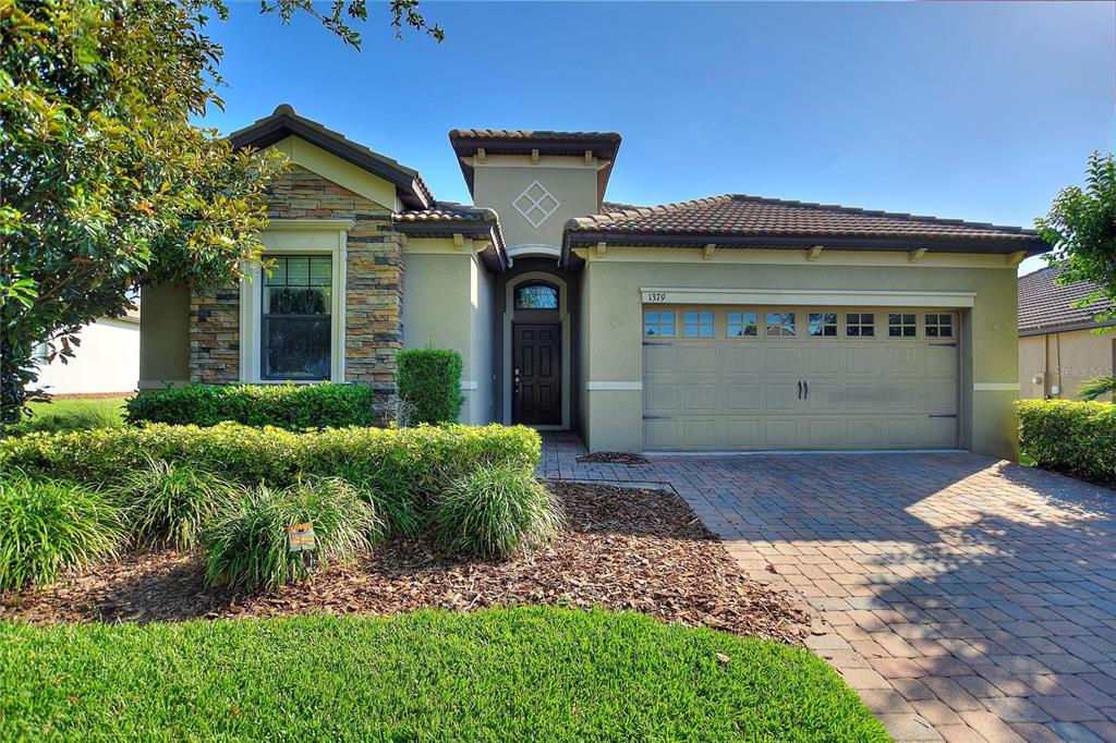 A single-story house with a stone-accented facade, a two-car garage, and a paved driveway — 1379 PALMETTO DUNES STREET, DAVENPORT, FL