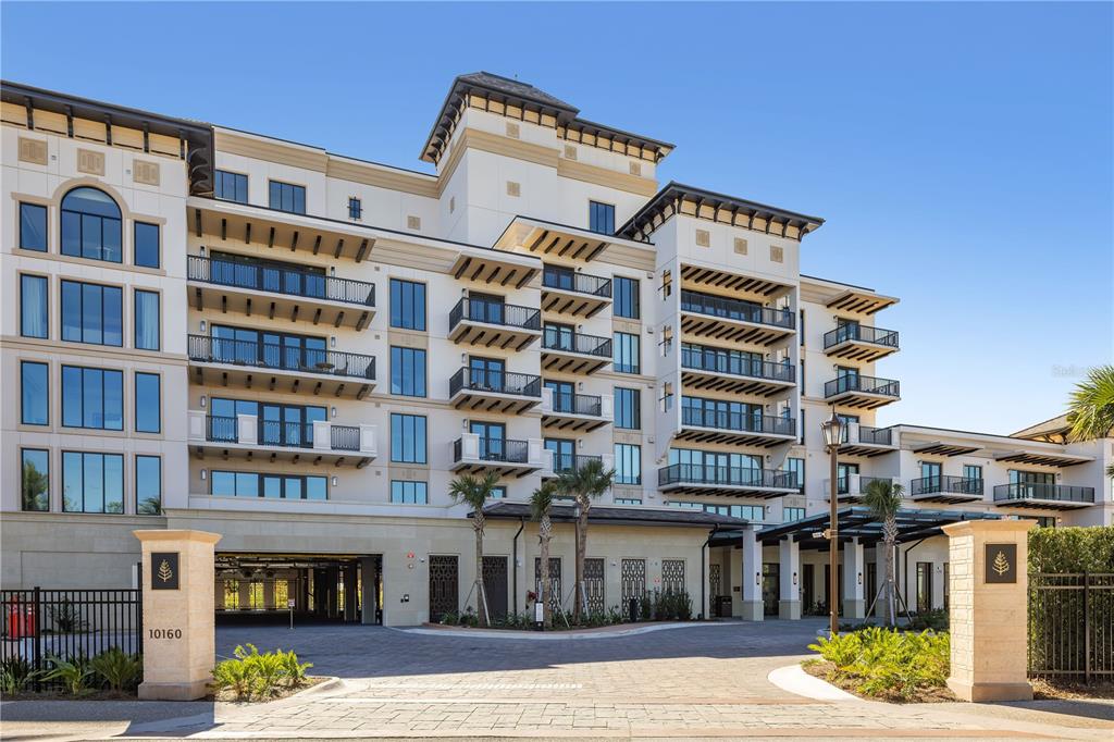 A multi-story apartment building with balconies and a gated entrance driveway — 10160 AUTUMN MIST LANE UNIT 402, ORLANDO, FL