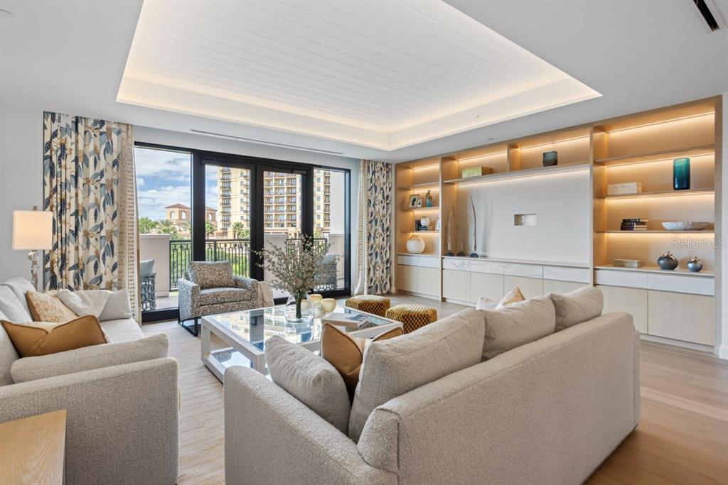 A living room features light-colored sofas, a glass coffee table, and built-in illuminated shelving — 10160 AUTUMN MIST LANE UNIT 402, ORLANDO, FL