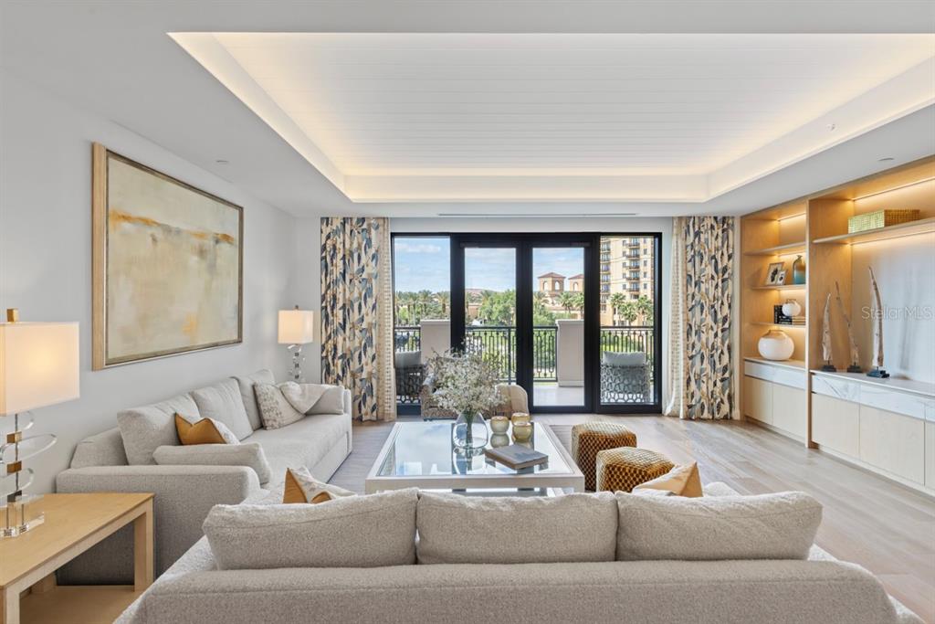 A living room features light-colored sofas, a glass coffee table, built-in shelving, and balcony doors — 10160 AUTUMN MIST LANE UNIT 402, ORLANDO, FL