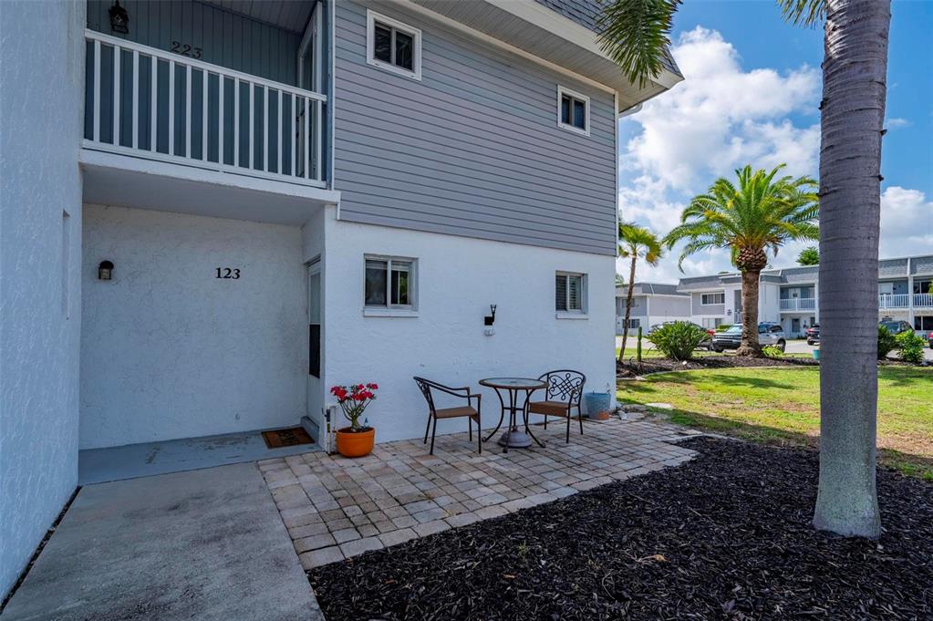 A ground-level patio with a table and chairs sits outside a two-story residential building — 22375 EDGEWATER DRIVE UNIT 123, PORT CHARLOTTE, FL