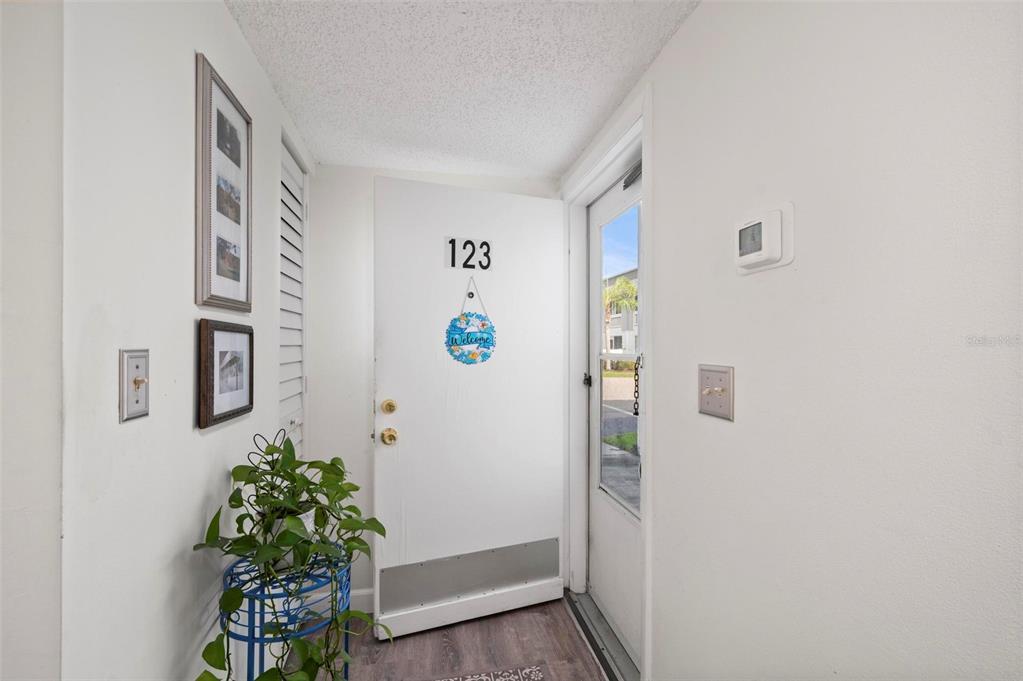 An entryway features a white door with the number 123, a plant, and wall art — 22375 EDGEWATER DRIVE UNIT 123, PORT CHARLOTTE, FL