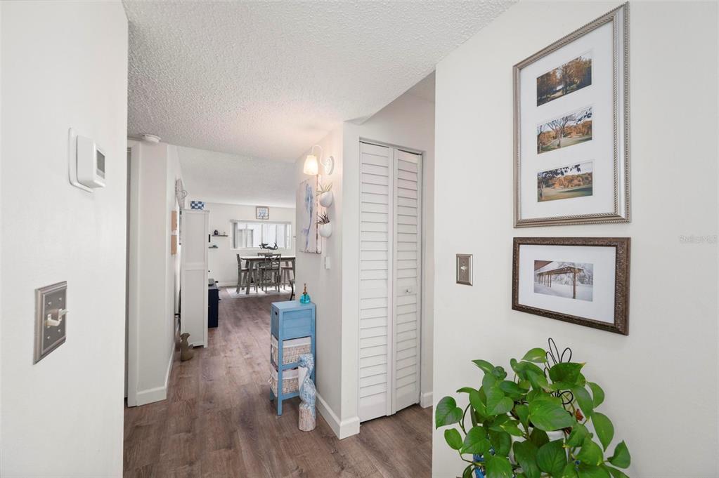 A hallway with wood-look flooring leads to a dining area with a white louvered closet — 22375 EDGEWATER DRIVE UNIT 123, PORT CHARLOTTE, FL