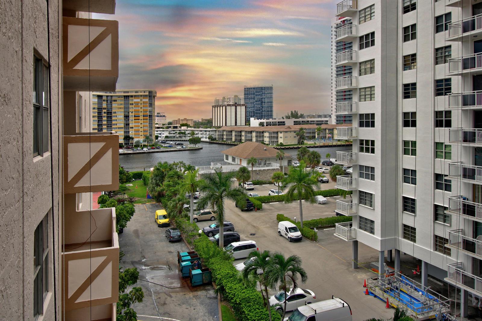 An elevated view of a parking lot, a canal, and surrounding apartment buildings at sunset — 1865 S Ocean Drive # 6c, Hallandale Beach FL 33009, HALLANDALE BEACH, FL