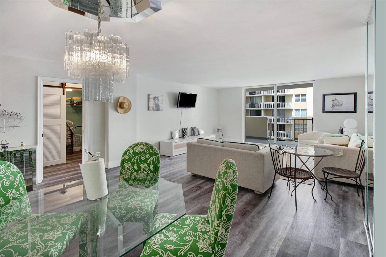 A bright living and dining area features green patterned chairs, a glass table, and balcony access — 1865 S Ocean Drive # 6c, Hallandale Beach FL 33009, HALLANDALE BEACH, FL