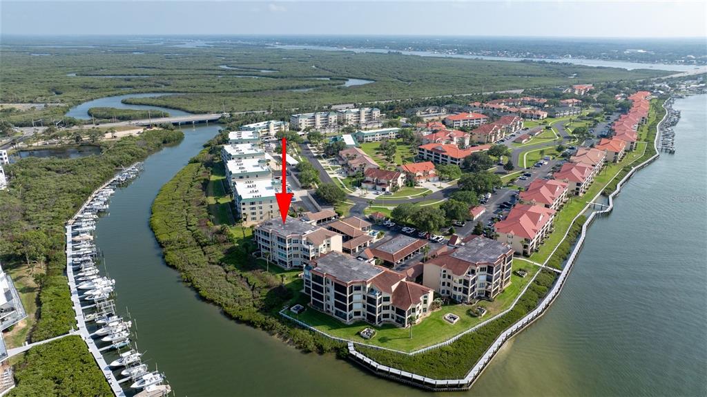 An aerial view shows a waterfront condominium complex surrounded by mangroves and a boat dock — 434 BOUCHELLE DRIVE UNIT 203, NEW SMYRNA BEACH, FL
