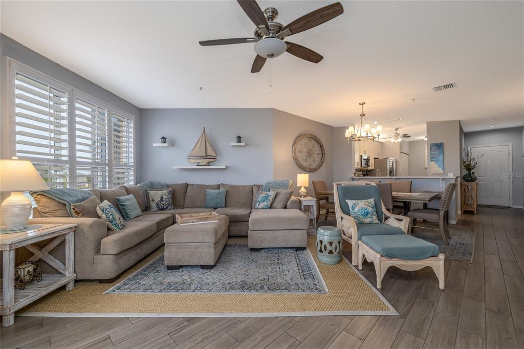 A living room with a sectional sofa, a ceiling fan, and an adjacent dining area — 434 BOUCHELLE DRIVE UNIT 203, NEW SMYRNA BEACH, FL